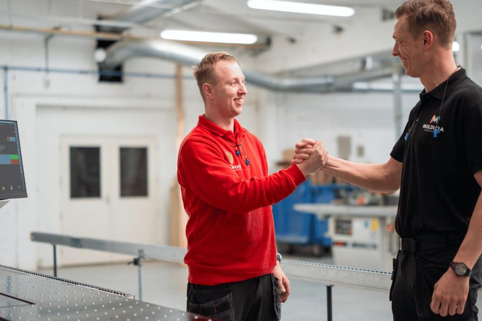 Twee mannen geven elkaar een hand naast een bewerkingsmachine in de showroom