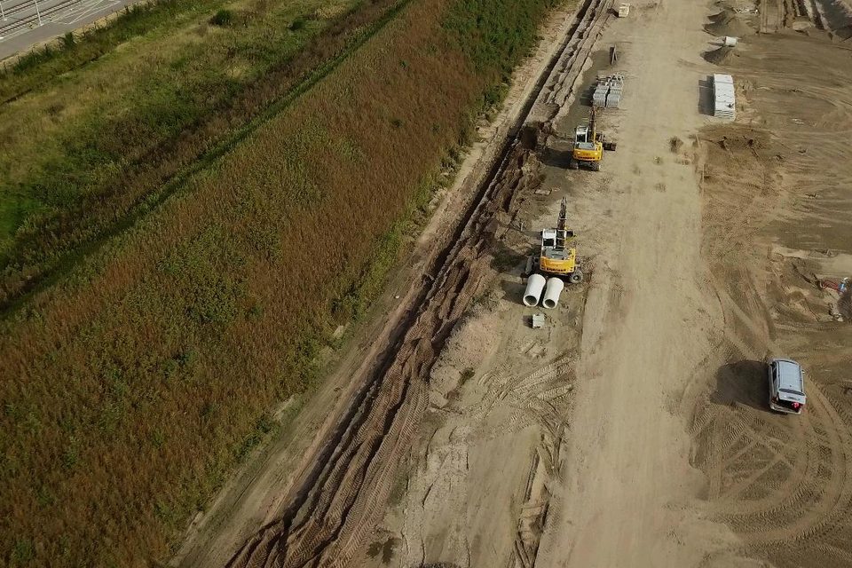 Luchtfoto van een infraproject met graafmachines en buizen langs het spoor